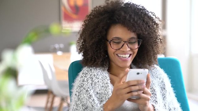 Beautiful mixed-race woman at home using smartphone