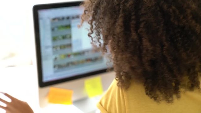 Cheerful mixed-race girl designing in office on computer