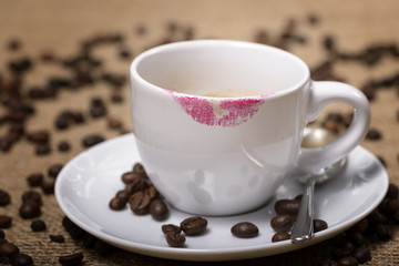 cup of coffee with lipstick traces and coffee beans around
