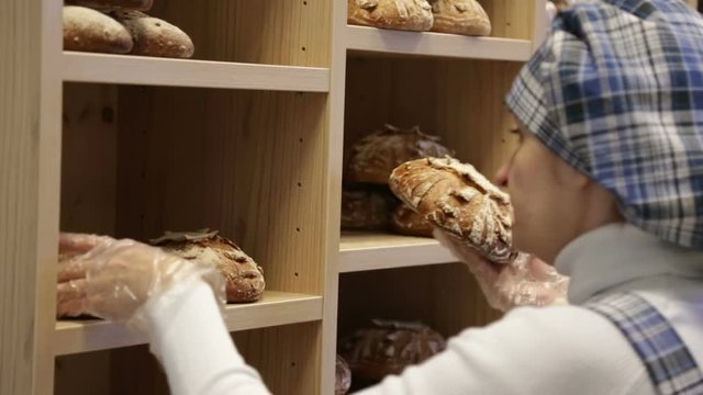 The baker puts bread on the shelves of his store