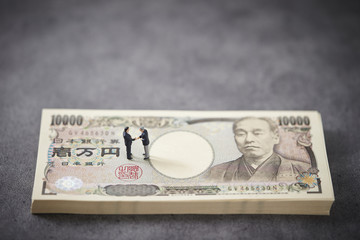 握手する男性たちと一万円札