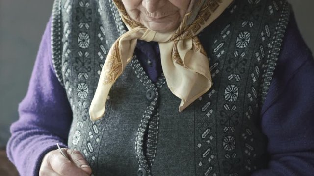 Old woman stiring eggs in the metal mug with shaked hands