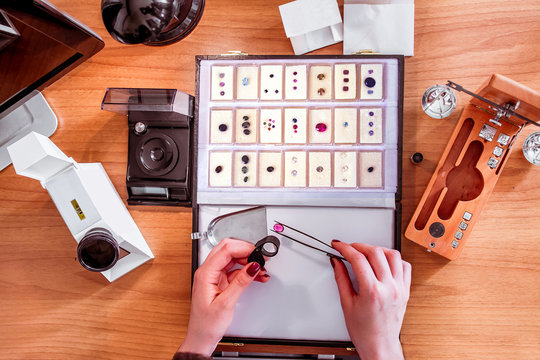 a gemologist examines a ruby using tweezers and evaluating gemstones top view on work table