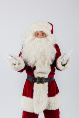 Santa Claus in eyeglasses and red costume throwing up hands on white background and looking into camera. American shot