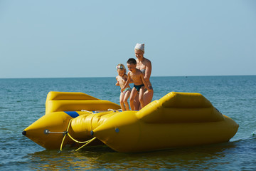 two children with mom on the dinghy sailing at sea in summer