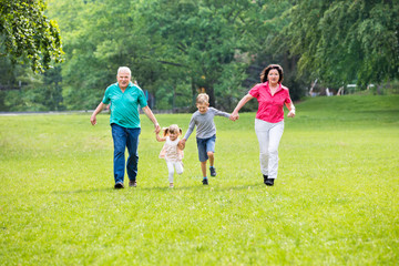 Obraz premium Grandparents And Grandchildren Running In Park