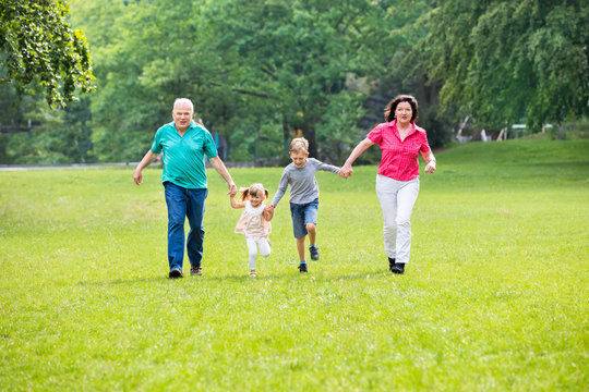 Grandparents And Grandchildren Running In Park