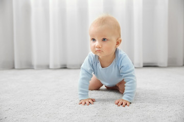 Fototapeta premium Adorable little baby crawling on light carpet