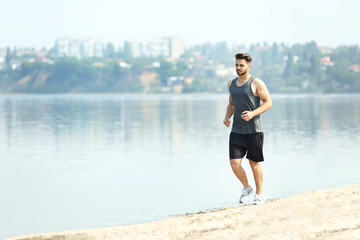 Handsome man jogging on river bank