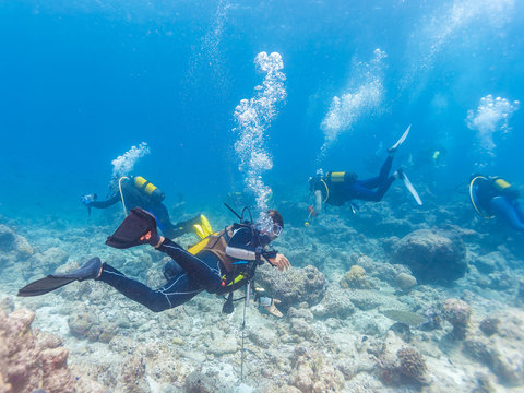 Group of underwater scuba divers with guide, Maldives