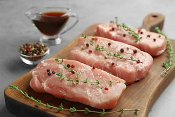 Steaks in marinade on wooden board and grey background