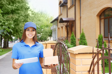 Female courier in uniform delivering parcels outdoor