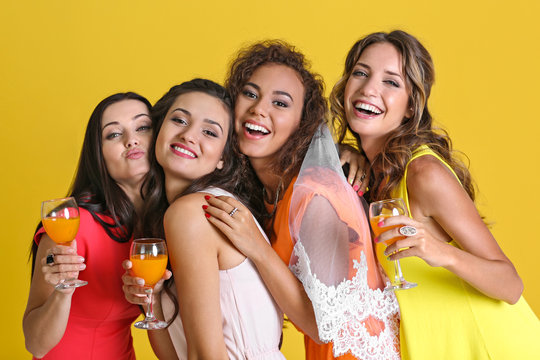 Beautiful girls with cocktails on yellow wall background
