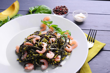 Black pasta with shrimps and avocado sauce on plate closeup