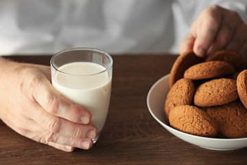 Senior man holding glass of milk and cookie