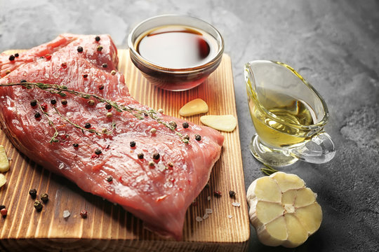 Tasty Steak With Marinade Ingredients On Board And Grey Background