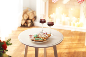Two glasses of wine and plate of Christmas cookies on table in room