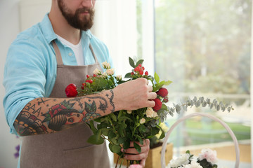 Male tattooed florist holding bouquet of beautiful flowers, close up view