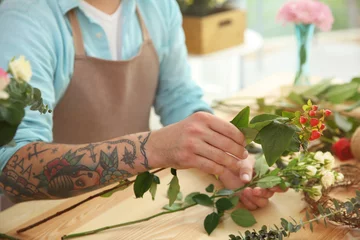 Photo sur Plexiglas Fleuriste Close up view of tattooed florist preparing flower composition at workplace