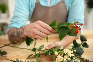 Close up view of tattooed florist preparing flower composition at workplace