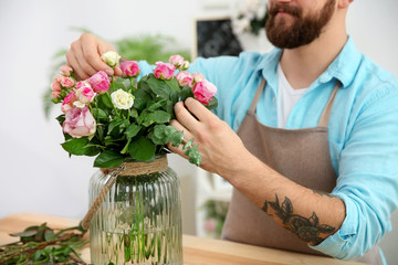 Close up view of tattooed florist preparing beautiful flower bouquet