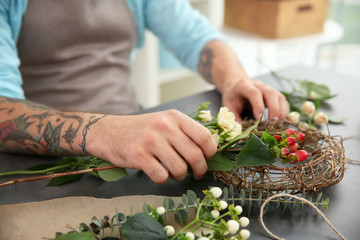 Close up view of tattooed florist preparing flower composition at workplace