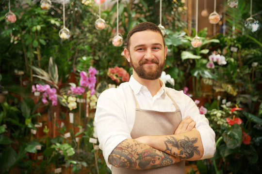 Handsome tattooed florist in greenhouse