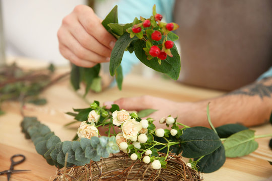 Close up view of tattooed florist preparing flower composition at workplace