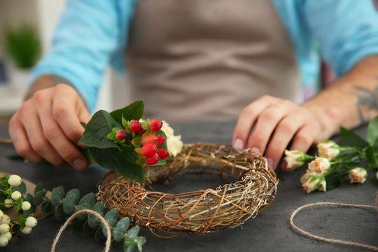 Close up view of tattooed florist preparing flower composition at workplace