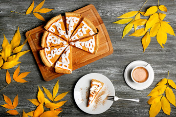 Sliced delicious pumpkin cake with cream decoration on wooden cutting board