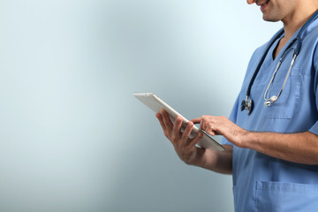 Doctor with tablet on light background