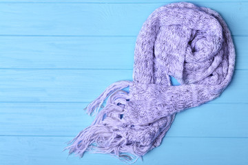 Colorful knitted scarf on blue wooden background