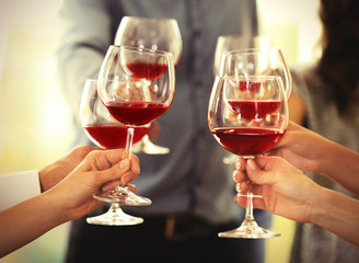 People toasting with glasses of red wine, closeup