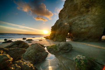 Last Light as sun sets behind the cliffs at El Matador State Beach near Malibu California - obrazy, fototapety, plakaty