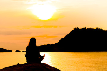 Silhouette, Woman Meditating in Yoga pose or Lotus Position by t