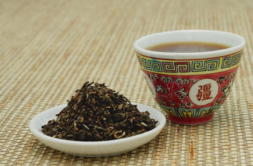Tea leaves on plate and Chinese teacup, still life