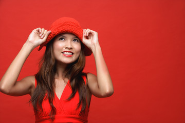 Obraz na płótnie Canvas Woman in red dress with red hat against red background, smiling