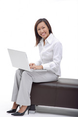 Business woman sitting on bench with laptop, smiling at camera