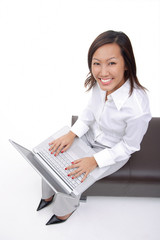 Woman sitting on bench with laptop, smiling at camera