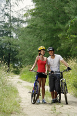 Couple standing with bicycles, smiling at camera