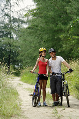 Fototapeta premium Couple standing with bicycles, smiling at camera