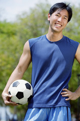 Man holding soccer ball, looking at camera
