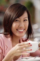 Woman holding coffee cup, smiling at camera