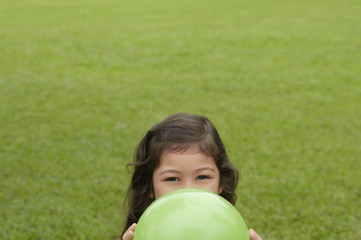 Girl hiding behind green balloon