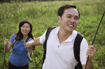 Man and woman hiking outdoors, holding hands, smiling