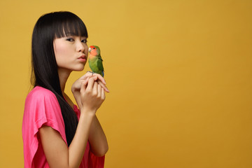 Young woman with lovebird on her hand, kissing bird