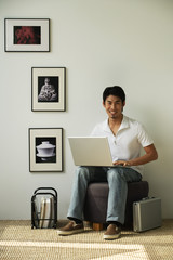 Young man with laptop on lap looking at camera
