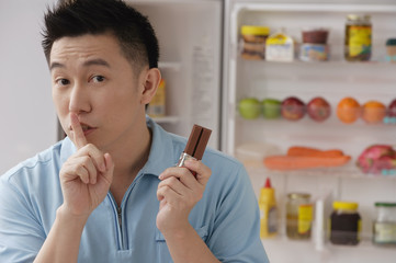 Man shushing while holding chocolate
