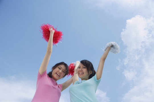 Young woman cheerleading with pom poms