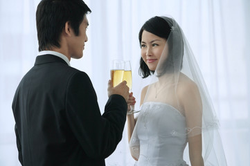 A newlywed couple hold out their champagne glasses for a toast
